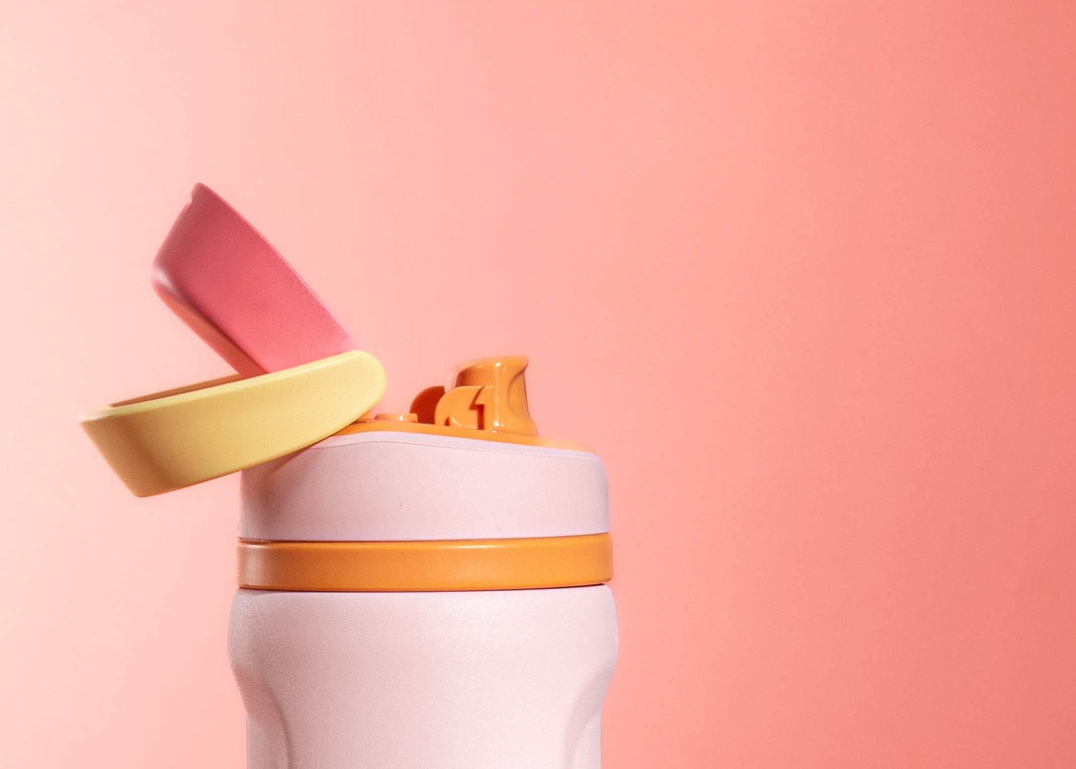 A light pink travel tumbler with a flip-up lid, shown with a small snack peeking out from the top. The tumbler features a yellow-orange band around the neck and the brand name 'MODE & OPAL' printed vertically on the front.