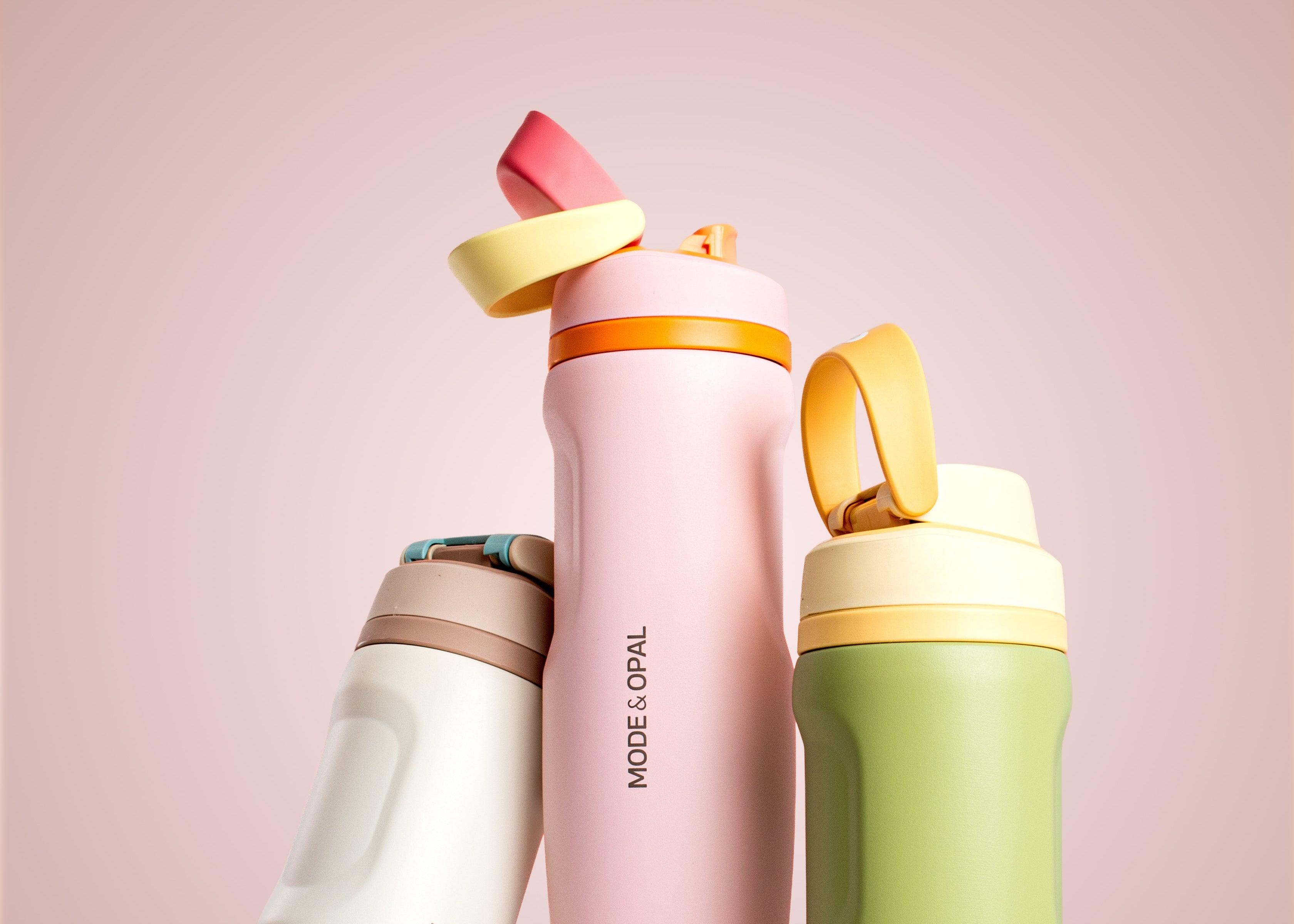 Three colorful water bottles with 'MODE & OPAL' branding on a light pink background